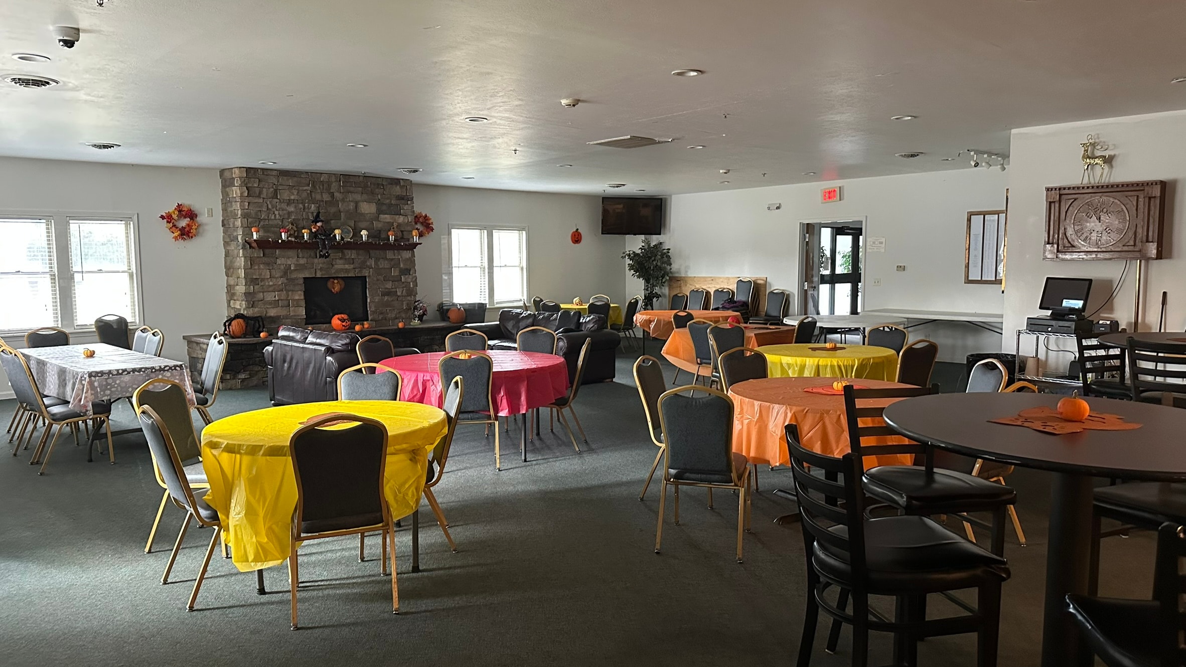 Watertown Elks Lodge game room with round tables, stone fireplace, leather seating, and flat screen TV